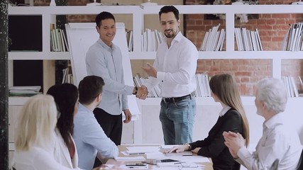 Wall Mural - Proud manager promoting handshaking successful male worker at team meeting