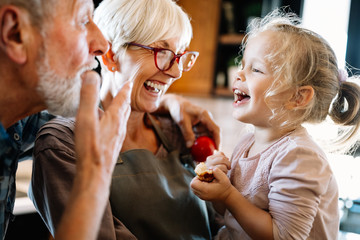 happy grandparents playing with their little cute granddaughter