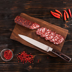 Wall Mural - Fresh red meat sausage being sliced with knife on wooden cutting board