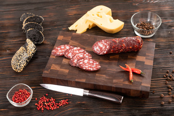 Wall Mural - Sliced cheese, sausage and bread on a wooden cutting board