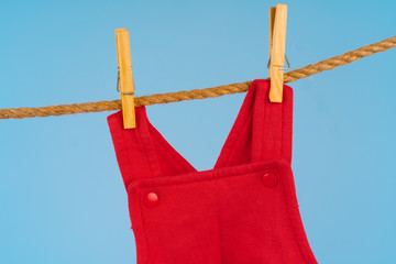 Wall Mural - Baby girl clothes pinned on a clothesline against blue background