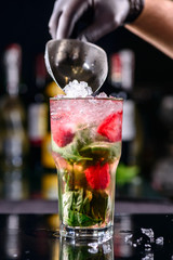 Sticker - hand of a bartender pours strawberry mojito closeup