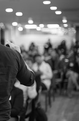 Fototapete - Speaker giving a talk at a corporate business conference. Audience in hall with presenter in front of presentation screen. Corporate executive giving speech during business and entrepreneur seminar. 