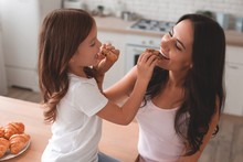 Portrait Of Mother And Daughter Feeding Each Other With Biscuits On The Kitchen