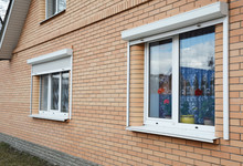 Rolling Shutters Brick House Windows Protection. Brick House With Metal Roller Shutters On The Windows For Protection