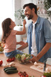 © Afshar Tetyana - happy father and daughter tasting freshly prepared salad on the kitchen