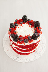 Wall Mural - homemade red velvet cake decorated with berries on a light wooden background