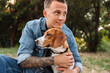 © Drobot Dean - Photo of beautiful young man smiling and hugging his canine dog in park