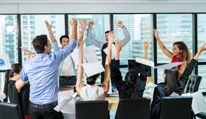 Multiethnic diverse Group of business people celebrating by throwing papers in the air and having fun in office.Happy business people cheering together,celebrate project success.