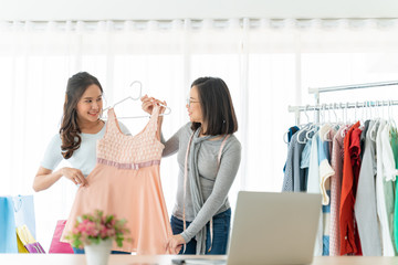 Social network sharing and online community concept.Asian girl show a dress in her live clip in social media with shop in home background,Young woman working as online shopping,sales,vlog and blogger.