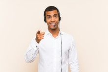 Young Brunette Man Working With A Headset Surprised And Pointing Front