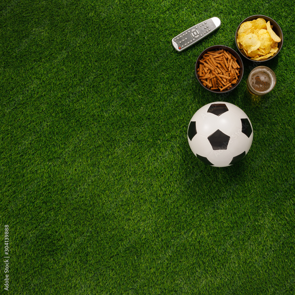 Soccer ball on a green field and ottoman for a fan with snacks and a TV ...