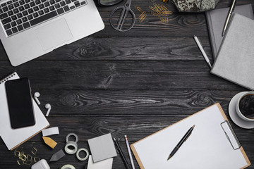 Flat lay composition with laptop. smartphone and stationery on black wooden table, space for text. Designer's workplace