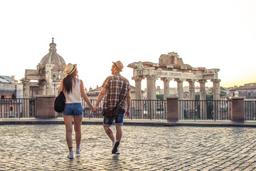 Young couple tourist walking towards Roman Forum at sunrise. Historical imperial Foro Romano in Rome, Italy from panoramic point of view.