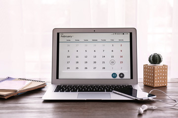 Canvas Print - Laptop with calendar on wooden table at workplace