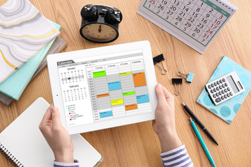 Woman using calendar app on tablet at table, closeup