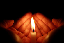 Two Hands Around A Burning Candle