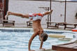 © Nataliia_Trushchenko - athletic build strong boy stands in his arms in a twine on the edge of the pool on a hot day at the water park on vacation