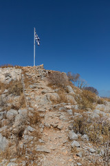 Wall Mural - Greek flag and ruins over a mountain in Hydra Island