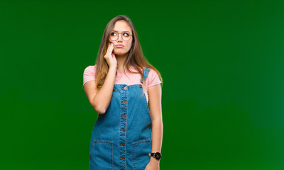 Wall Mural - young pretty woman holding cheek and suffering painful toothache, feeling ill, miserable and unhappy, looking for a dentist against green background