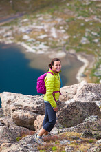 A Woman Poses With A Small Day Pack While Descending From The Summit Of Pyramid Peak (12,030) In The WInd River Range During A Backpacking Trip In August. Pyramid Lake Is Pictured In The Background.