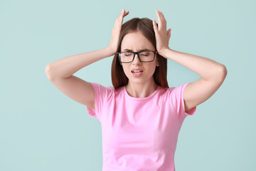 Wall Mural - Young woman suffering from headache on color background