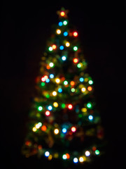 vertical view of blurred christmas tree with garlands in dark. abstract christmas background with de