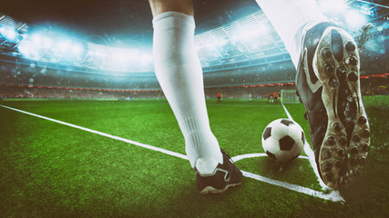 Football scene at night match with close up of a soccer shoe hitting the ball from corner kick