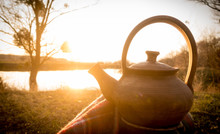 Hot Teapot At Autumn Sunset On Riverbank