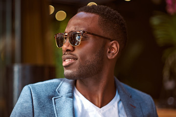 Wall Mural - Portrait of young confident american businessman in sunglasses and blue blazer.