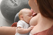 Young woman breastfeeding her baby at home, closeup