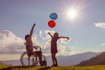 Two sister children playing with colored balloons at sunset.