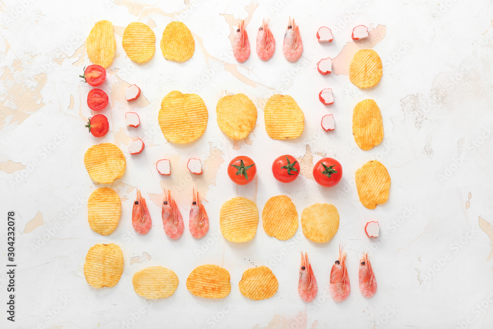 Tasty potato chips, shrimps, crab sticks and tomatoes on table