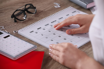 Canvas Print - Woman with calendar at wooden table, closeup