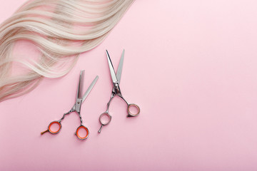 Wall Mural - Scissors and other hairdresser's accessories and strand of blonde hair on pink background. Flat lay with space for text. Hairdresser service. Beauty salon service