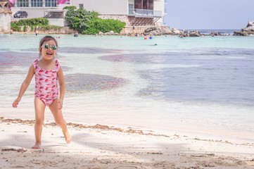 Happy little girl laughing with sunglasses on the beach