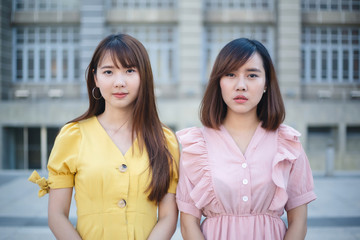 Portrait of two young girl friends posing together with the background of urban city