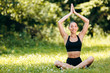 © speed300 - Pretty brunette woman  doing yoga asana sitting in the park outdoor.Hands up over  the head