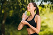 © speed300 - Sporty woman drinks water outdoor with pleasure. - Image