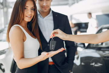 Wall Mural - People in a car salon. Man buying the car. Elegant women with handsome man