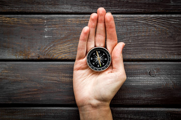 Wall Mural - Choose direction concept. Compass in hand on dark wooden background top view copy space
