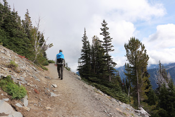 man climbing a mountain trail near mount rainier, washington state, usa