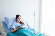 © Thinapob - asian young female patient on bed with hand holding a cup coffee or tea in hospital background