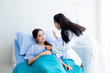 © Thinapob - Asian young female patient on bed while doctor hands of checking examining his pulse for record the treatment results with smiley face very good symptom in hospital background.