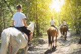Group of teenagers on horseback riding in summer park