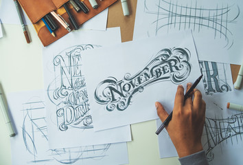 Wall Mural - Typography Calligraphy artist designer drawing sketch writes letting spelled pen brush ink paper table artwork.Workplace design studio.