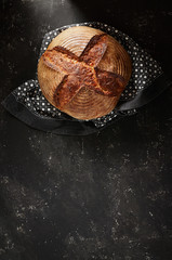 Freshly baked Artisan sourdough bread loaves with kitchen towel on black concrete backgroun