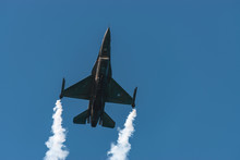 F-16 Fighting Military Fighter Jet Airplane Flying With Smoke Against Blue Sky Background.