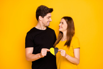 Poster - Photo of cheerful cute charming pretty couple of beautiful people looking at each other affectionately embracing holding multicolor heart symbolizing love isolated vivid color background