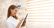 © borevina - A beautiful young brunette nurse is happy while she has a tablet in her hands and checks the patient's test results. She is in a modern health and beauty care clinic.